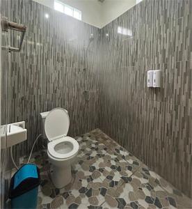 a bathroom with a toilet and a tile wall at FOUR-G Home Stay & Komodo Tour in Labuan Bajo +179 photos