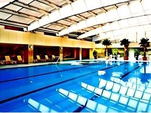 a large swimming pool with chairs in a building at Maihao International Hotel in Zhuhai
