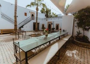 a room with a table and chairs and palm trees at Riad TAWALA Surfing Mind in Tamraght Ouzdar