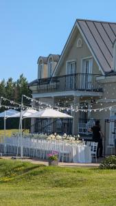 a table with white tables and umbrellas in front of a building at Provansalio dvaras in Babriškės