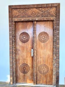 een houten deur met ingewikkelde ontwerpen erop bij Diamond Luxury Homes in Watamu