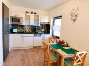 ゾントホーフェンにあるAppartement Alpblickの白いキャビネットと木製のテーブルのあるキッチン