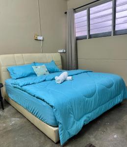 ein Bett mit einer blauen Bettdecke und blauen Kissen in der Unterkunft Little Stay Inn in Taiping