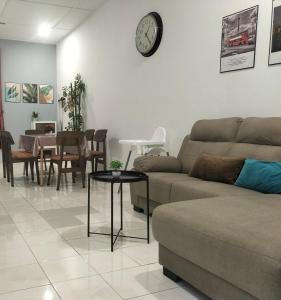 sala de estar con sofá, mesa y reloj en Room&Rest Homestay Seremban Mutiara Galla, en Seremban