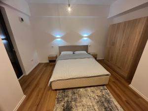a small bedroom with a bed and wooden floors at Central BB Apartment with Free Parking in Târgu-Mureş