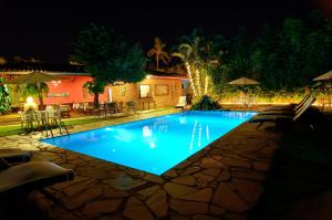 a swimming pool at night with chairs and umbrellas at Pousada Casa de Maria in Prado