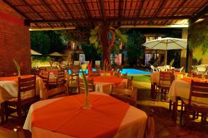 a restaurant with tables and chairs and a pool at Pousada Casa de Maria in Prado