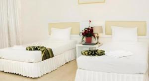 two white beds in a white room with flowers on them at Seng Aroun Hotel in Pakse +39 photos