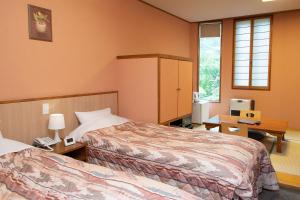 um quarto de hotel com duas camas e uma escrivaninha em ゆのホテル奥日光やまみず樹 em Yumoto