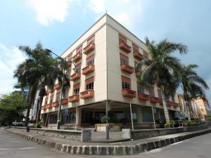 Un edificio con palmeras delante. en Hotel Formosa, en Malalayang