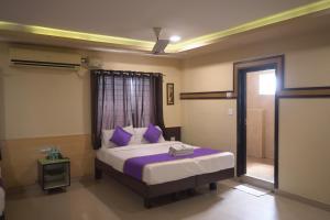 a bedroom with a bed with purple pillows and a window at Hotel UR Comforts Jayanagar in Bengaluru