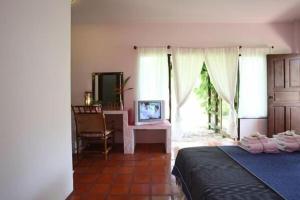 a bedroom with a bed and a desk and a window at Baan Chuengkao Resort in Ranong