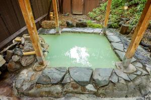 uma pequena poça de água verde em um quintal em ゆのホテル奥日光やまみず樹 em Yumoto