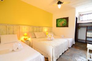 2 camas en una habitación con paredes amarillas en Pousada Casa de Maria, en Prado