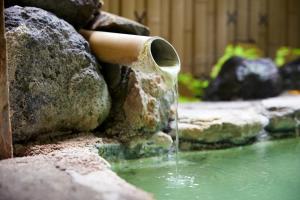 uma fonte de água num jardim com pedras em ゆのホテル奥日光やまみず樹 em Yumoto