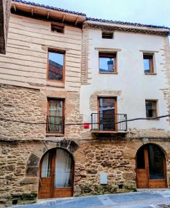 Una antigua casa de piedra con puertas y ventanas de madera. en Patio y Calados Rioja Suites, en Cenicero