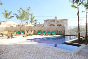 a swimming pool with chairs and tables and a building at Vitória Hotel Express Dom Pedro in Campinas
