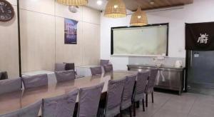 uma sala de conferências com uma mesa, cadeiras e uma tela em 7 Days Inn Tianjin Railway Station em Tianjin