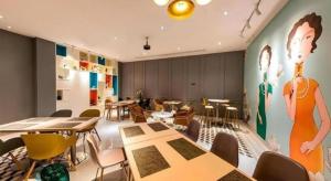 a restaurant with tables and chairs and a painting on the wall at Magnotel Fuzhou Wuyi Road Sanfangqixiang in Fuzhou