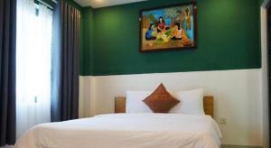 Un dormitorio con una cama blanca con una pared verde. en LaCas Hotel Quy Nhon, en Quy Nhon 44 fotos más