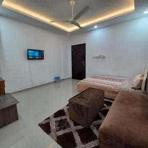 Zimmer mit 2 Betten, einem Sofa und einem TV in der Unterkunft Raha rooms in Seeb