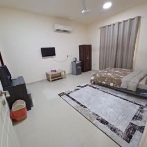 Schlafzimmer mit einem Bett, einem TV und einem Teppich in der Unterkunft Raha rooms in Seeb