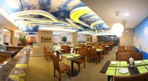 a restaurant with tables and chairs and a mural on the ceiling at Xiamen Plaza Hotel in Xiamen