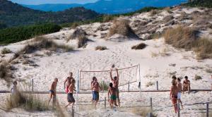 a group of men playing volleyball on a beach at Chia Laguna - Hotel Village in Chia