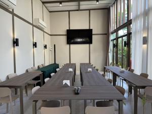 einen Konferenzraum mit Holztischen und -stühlen und einem Flachbild-TV in der Unterkunft Baanna Place in Ban Na