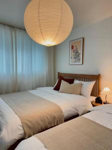 ein Schlafzimmer mit zwei Betten und einer großen Leuchte in der Unterkunft NEW Stay Rombus in Seoul