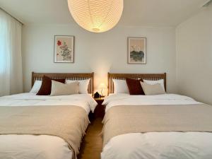 2 Betten in einem Zimmer mit weißen Wänden und einem Kronleuchter in der Unterkunft NEW Stay Rombus in Seoul