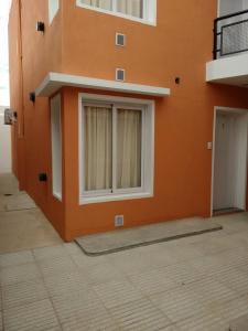 a building with an orange wall with a window at Nec Apart Hotel in Las Perdices