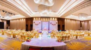 LONGYAN JINGHUA FLIPORT HOTEL في لونغيان: قاعة احتفالات كبيرة بها طاولات وكراسي