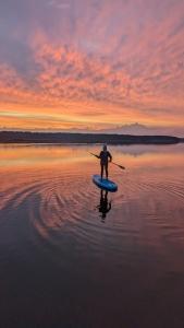 a person riding a paddle board on a body of water at Dom ukryty przed światem - Szeroki Bór in Ruciane-Nida +112 photos