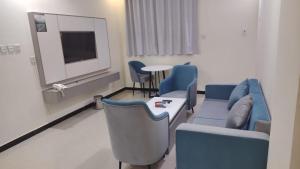 a waiting room with blue chairs and a tv at شقق راما الشرق المخدومة المملكة العربية السعودية حي الشفاء حائل in Hail