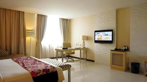 Kedaton Hotel في باندونغ: غرفة فندق بها سرير وتلفزيون على الحائط
