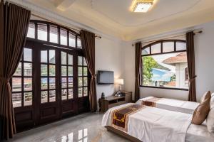 a bedroom with a bed and large windows at Vạn Xuân Royal Hotel in La Phù