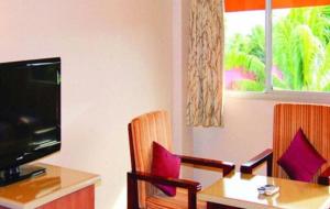 um quarto com uma mesa, uma televisão e cadeiras em Peninsula International Hotel em The Domain