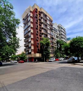 a tall building on a city street with cars parked at Del Paseo al Mar in Mar del Plata
