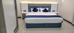 a bedroom with a large bed with blue and white pillows at شقق راما الشرق المخدومة المملكة العربية السعودية حي الشفاء حائل in Hail