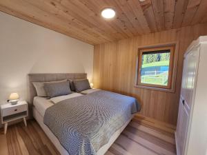 a bed in a small room with a window at Blickfang Bregenzerwald in Langenegg