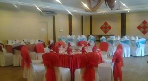 un salón de banquetes con mesas blancas y sillas rojas y blancas en Disini Hotel, en Sembulan