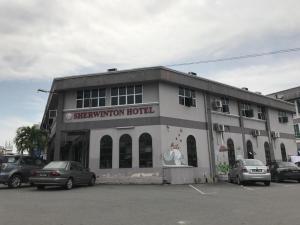 a building with cars parked in a parking lot at Sherrinton Hotel in Mentekab