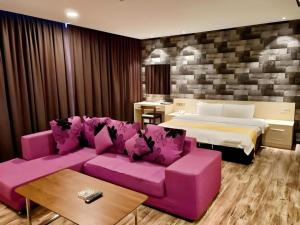 a living room with a pink couch and a bed at Kidurong Inn in Bintulu +89 photos