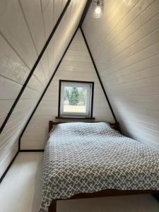 a bed in a small room with a window at Frame&Forest in Kolochava