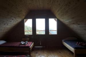 a attic room with two beds and a window at Quetzal Valley Cabins in San Gerardo de Dota