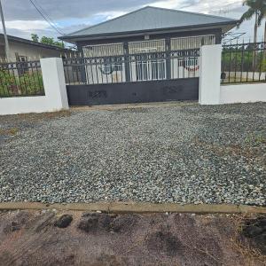 ein Haus mit einem Tor und einer Kieseinfahrt in der Unterkunft Jawala Mansion in Paramaribo