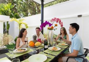 拉威海滩Modern Zen Oasis Villa Style - Pool, Rooftop Views & Playground - All-Inclusive - 4BR-3BA的一群人坐在桌子旁,戴着酒杯