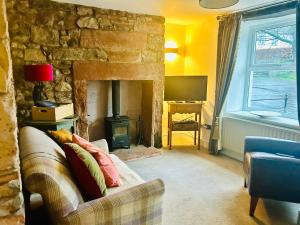 ein Wohnzimmer mit einem Sofa und einem Steinkamin in der Unterkunft L'al Cottage, Sockbridge in Penrith