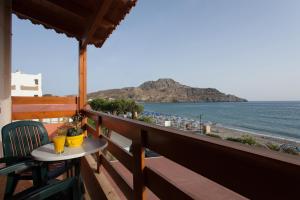 Un balcón con mesa y vista a la playa. en Flisvos Rooms, en Plakias